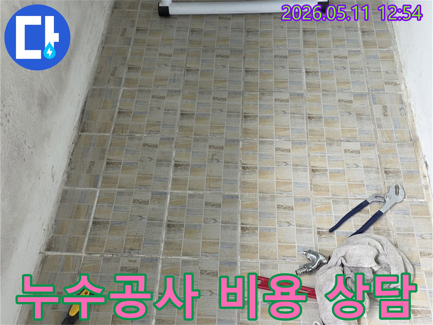 누수 공사 현장에서-타일 벽면과-작업에 필요한 공구들이 놓여있는 모습