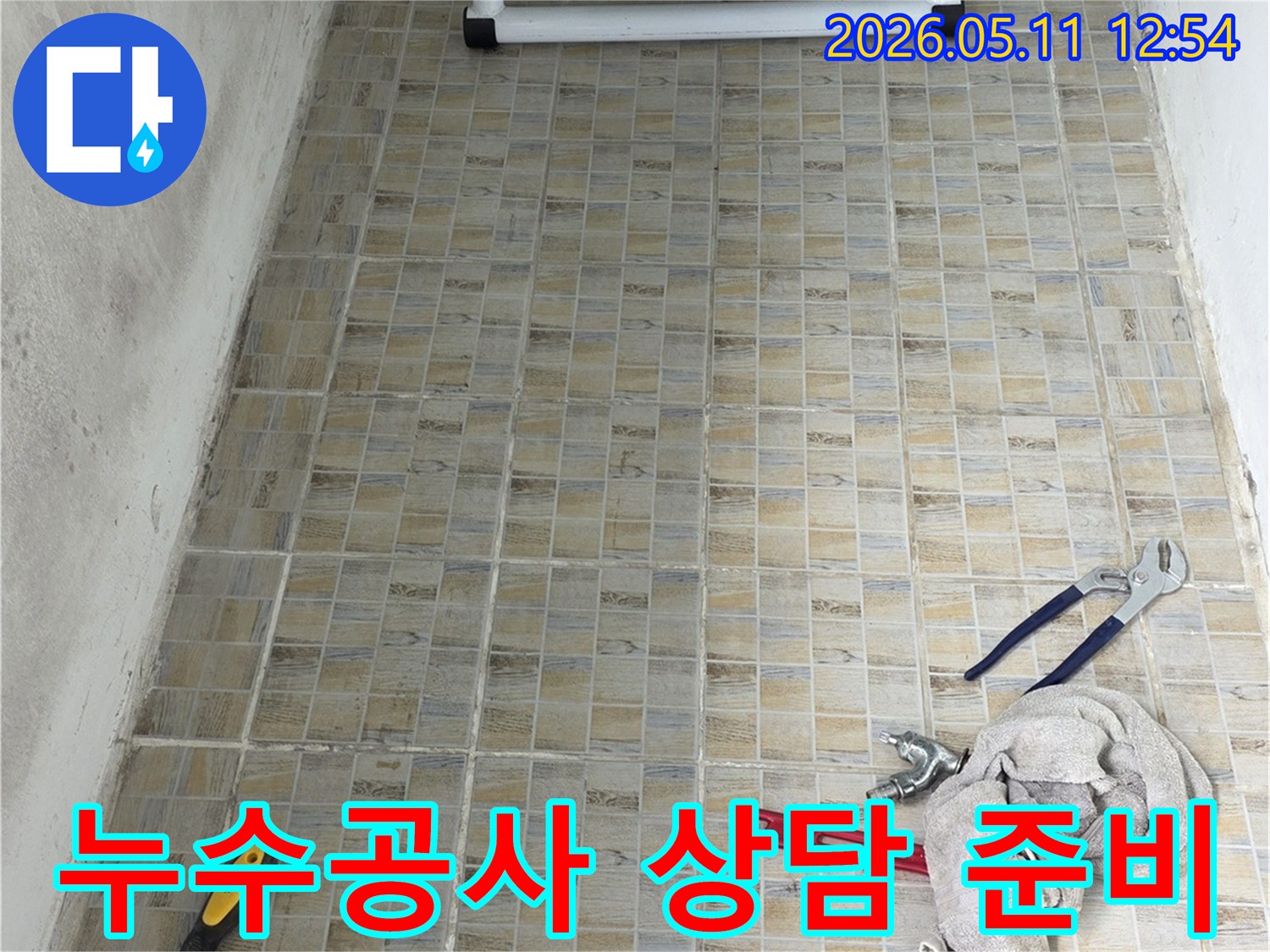 누수 공사 현장에서-타일 벽면과-작업에 필요한 공구들이 놓여있는 모습