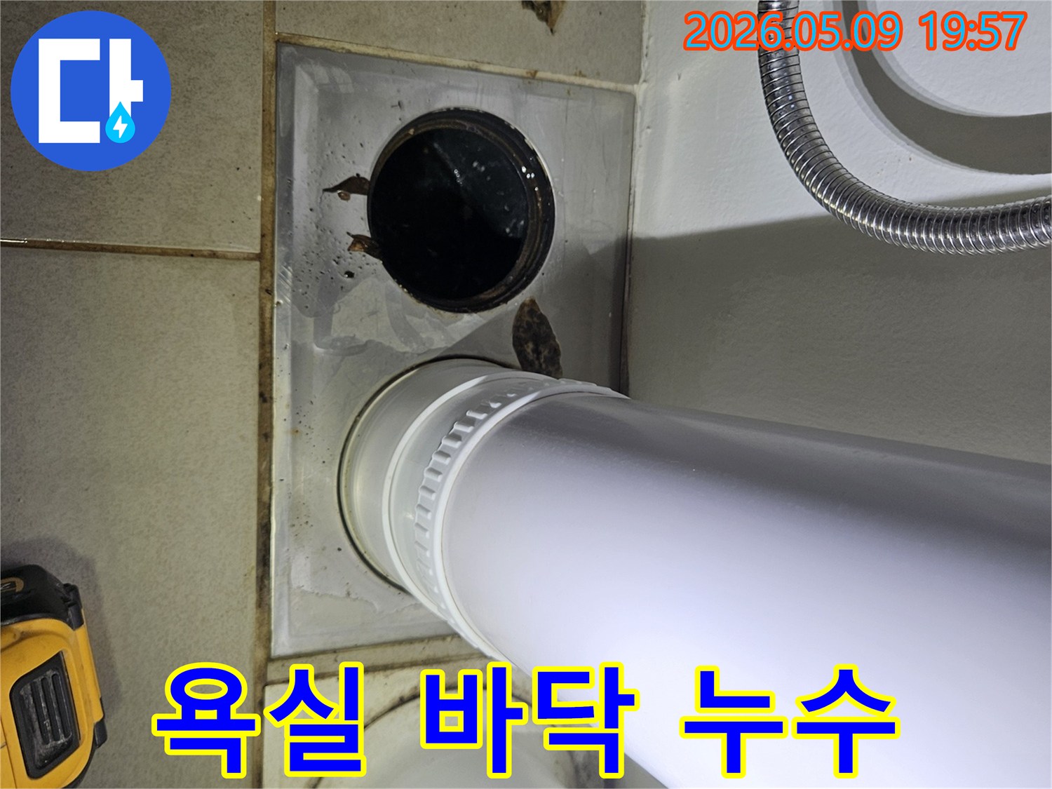 이 이미지는 욕실 바닥의 배수구와 인접한 배관 주변에서 발생한 물 고임 현장을 상세히 보여줍니다.