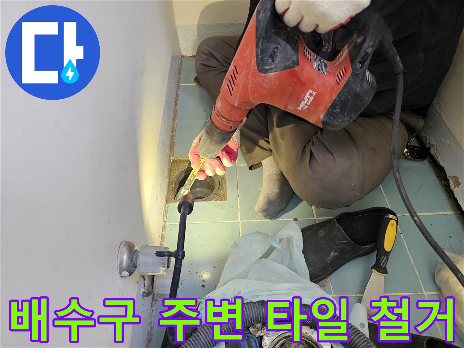 작업자가-함마드릴로 배수구 근처의 낡은 타일을 정교하게 제거합니다.