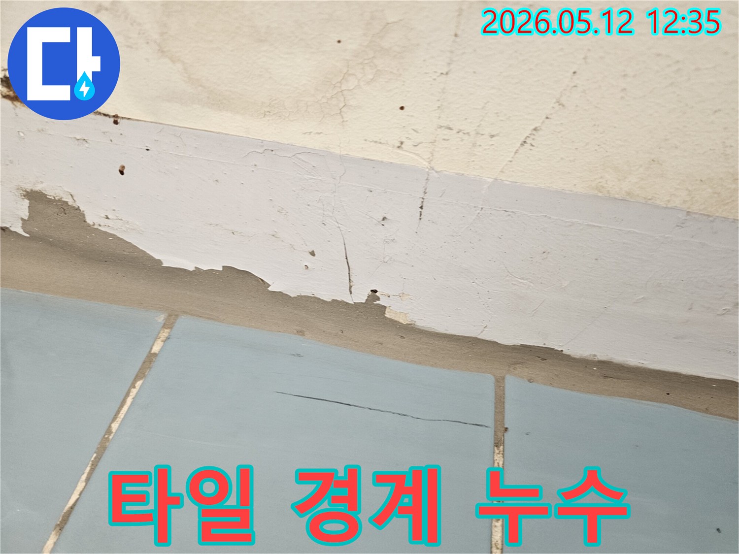타일과 벽면 경계에서 발생한 누수로-페인트가 손상된 상태를 나타냅니다