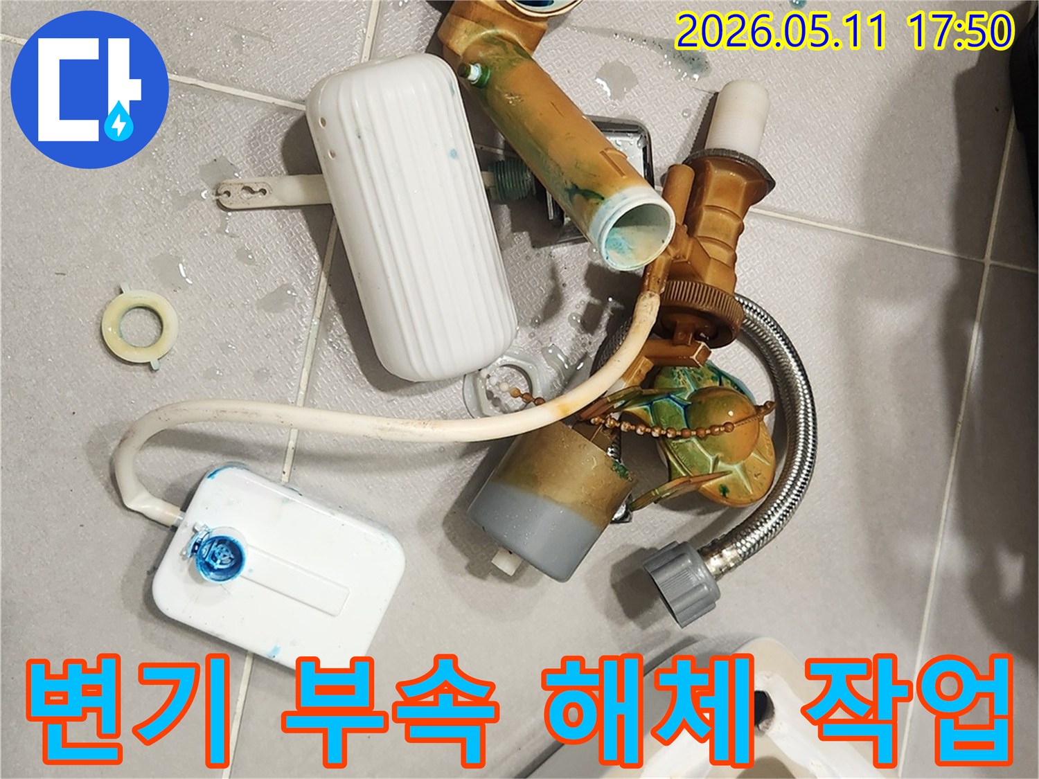 안방 변기에서 발생한 물샘 문제를 해결하기 위해-오래된 변기 부속들이 해체되어 바닥에 놓여 있는 모습입니다-새 부품으로 교체하여 변기를 수리할 예정입니다