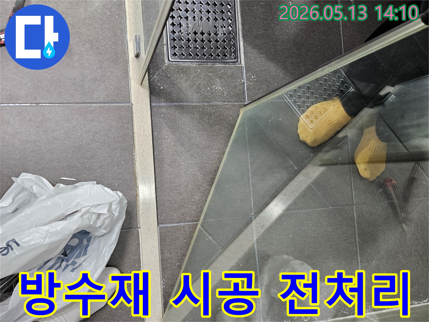 샤워 부스 하단부와 배수구 주변-새로운 방수재 시공을 위한-표면 처리 작업을 진행하는 모습입니다.