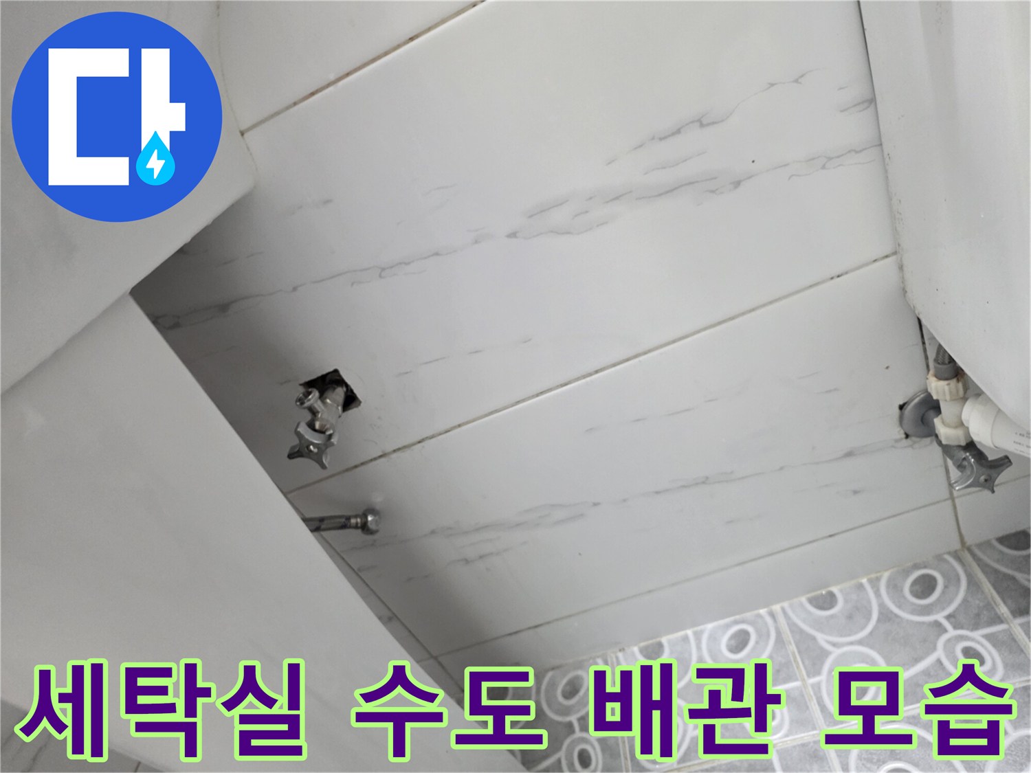 흰색 타일 벽면의 세탁실 수도 밸브와 배관 연결 부위 근접 촬영