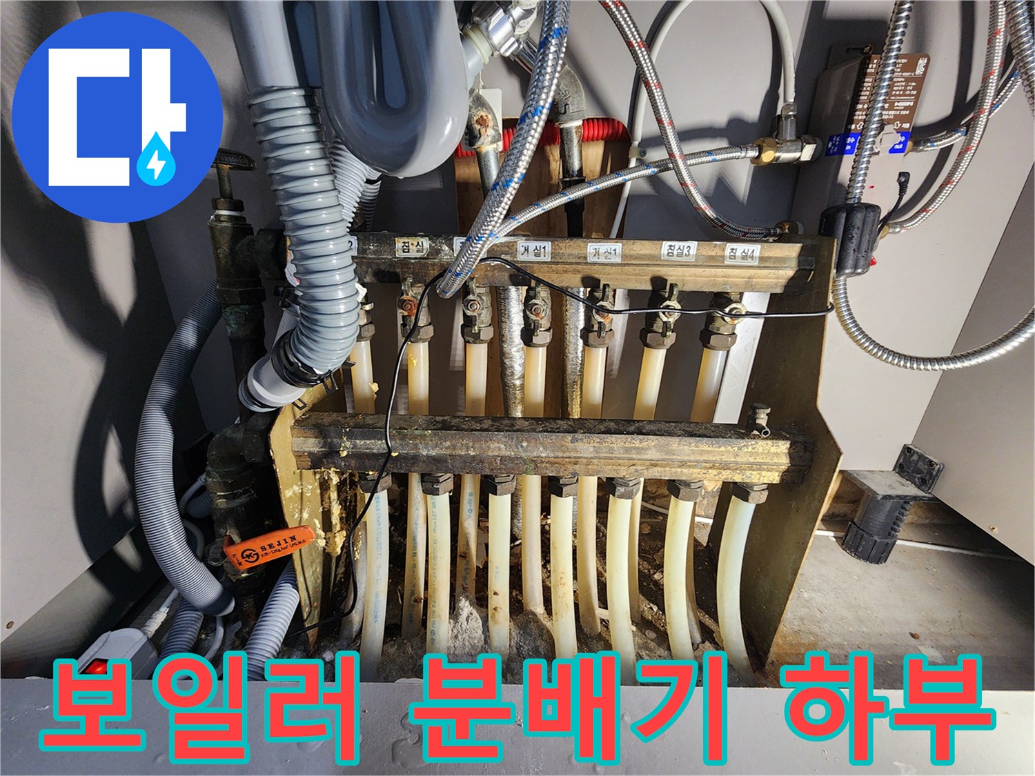 복잡하게 얽힌 난방 배관과 금속 분배기 밸브의 근접 촬영 사진입니다.