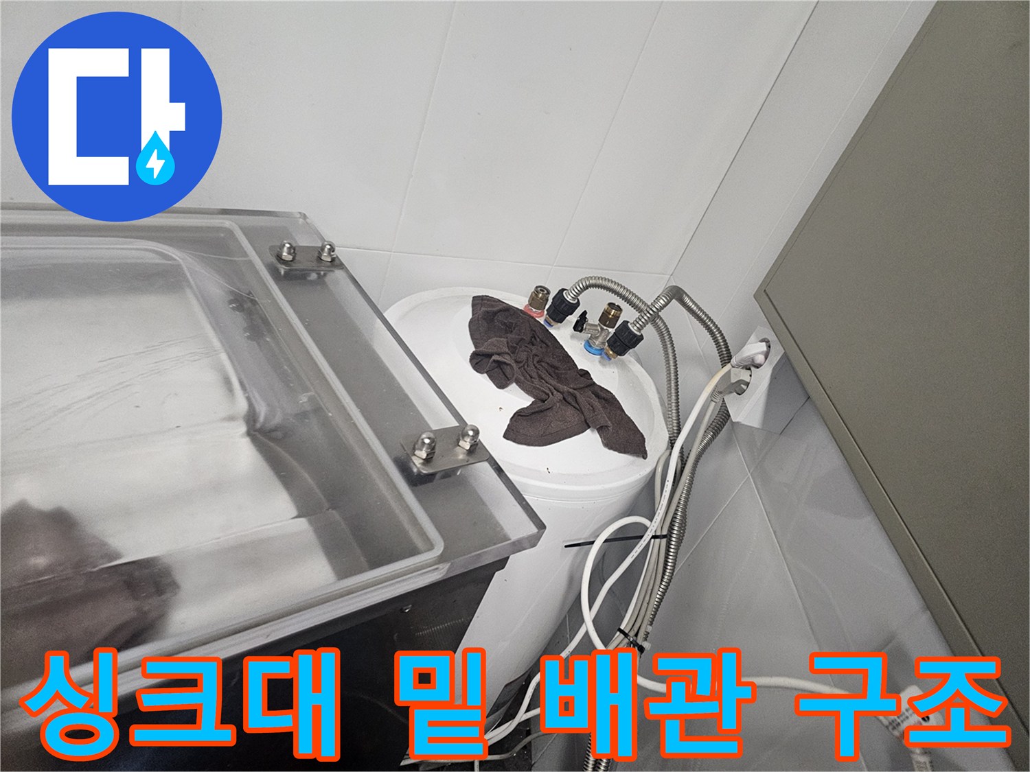 복잡하게 얽힌 싱크대 하단 수도 배관과 수전 연결 부위 사진입니다.