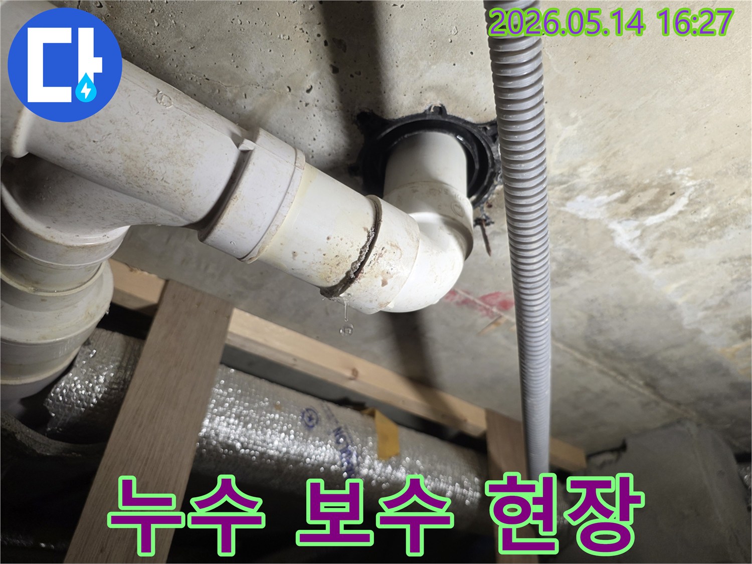 천장 아래 배관 이음새에서 물방울이 떨어지는-꼼꼼한 보수 작업이 필요한 누수 현장 사진