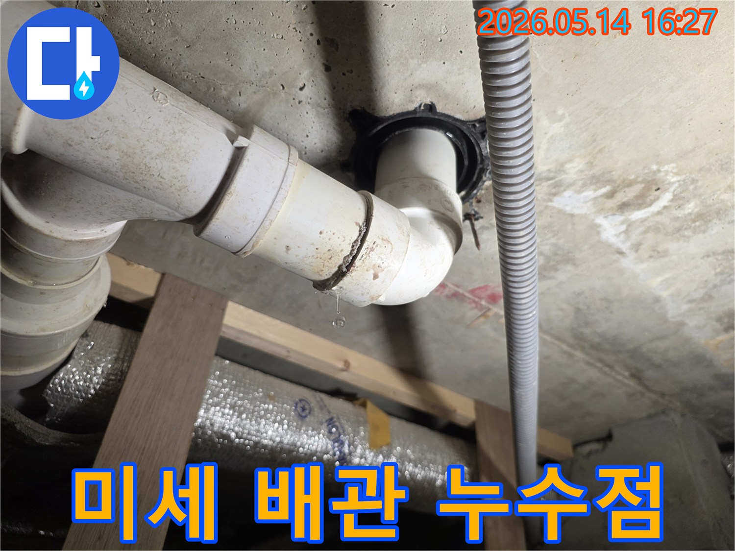천장 아래 배관 이음새에서 작은 물방울이 떨어지는-미세하지만 중요한 누수 현장을 보여주는 사진