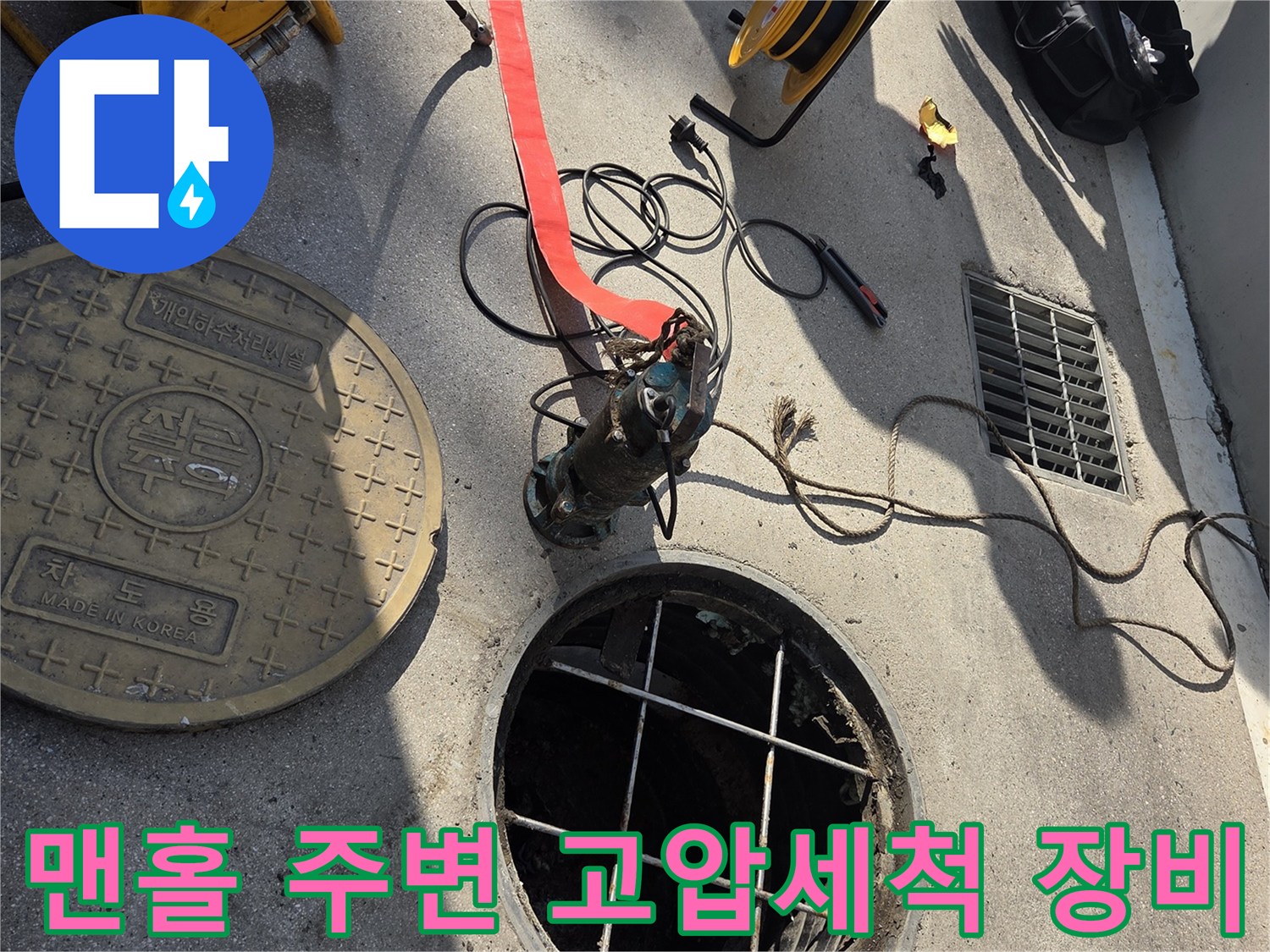 고압세척을 위해 맨홀 근처에 설치된 호스와 전문 장비 모습입니다.