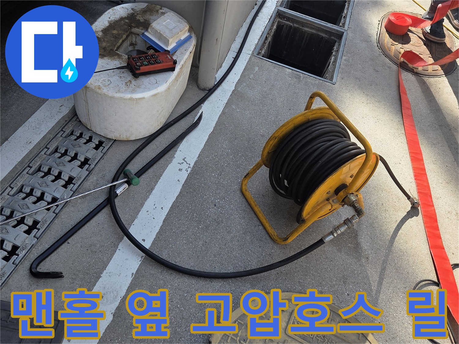 합정동 맨홀 작업 현장 - 고압 세척용 호스 릴이 배치되어 있습니다.