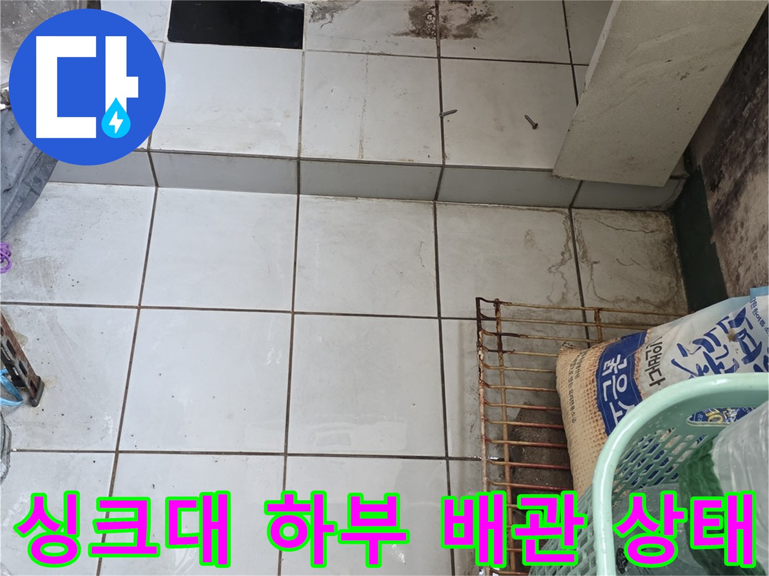 남양주 진건읍-싱크대 하부장 내부의 파란색 수도 배관과 타일 벽면 모습