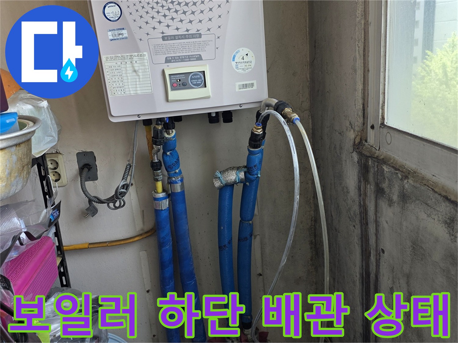 보일러 하단에 연결된 파란색 배관과 주름관의 체결 상태를 확인하는 모습