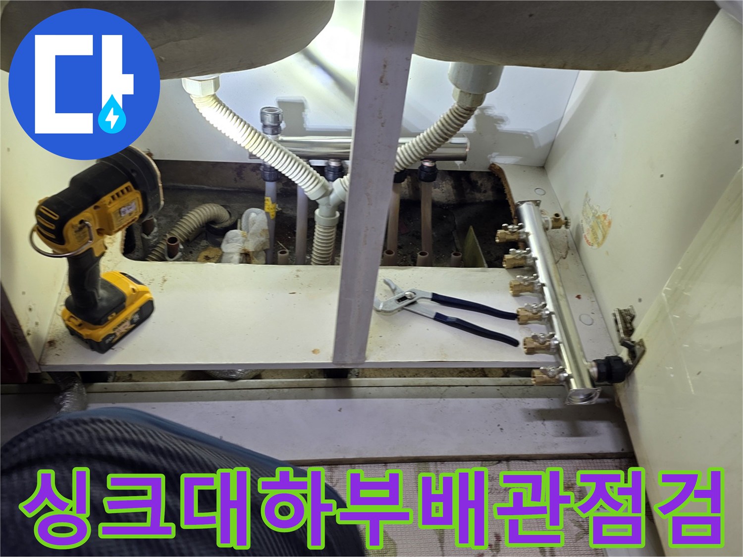 주방 싱크대 하부장 내부의 분배기와 연결된 배관 상태를 점검하는 모습