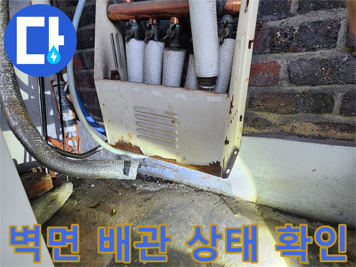 손전등 빛이 비치는 벽돌 벽과 노출된 보온 배관들