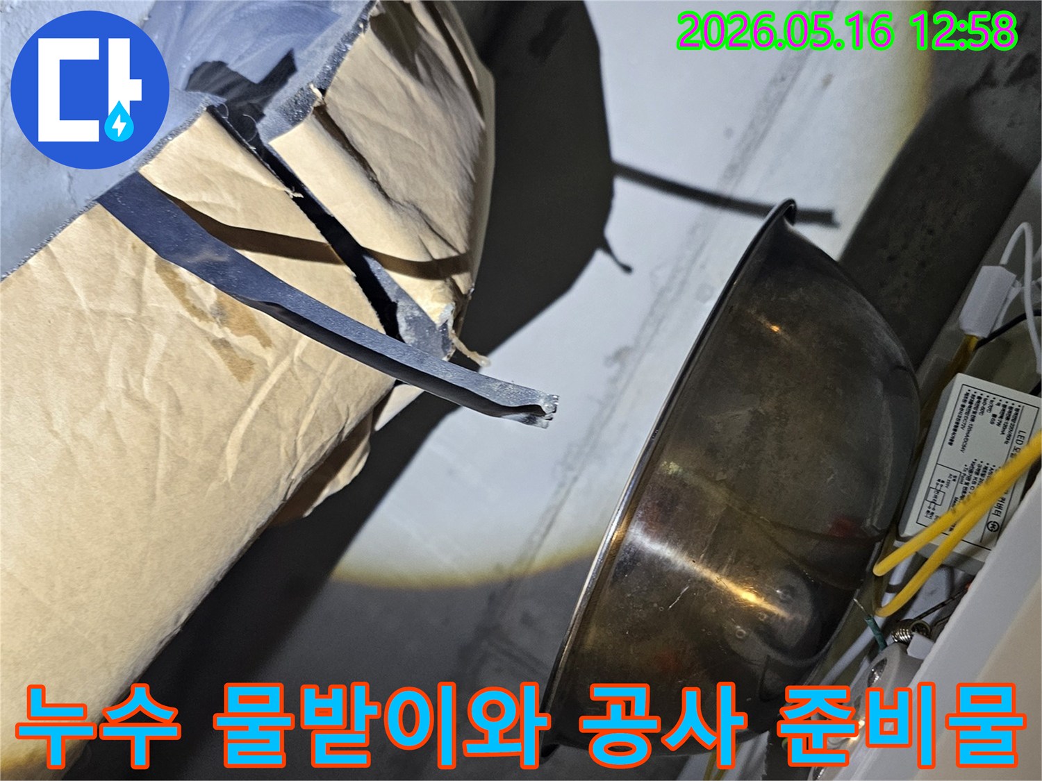 누수-지점에서-떨어지는-물을-안전하게-모으기-위해-설치된-금속-용기와-주변-공사-자재