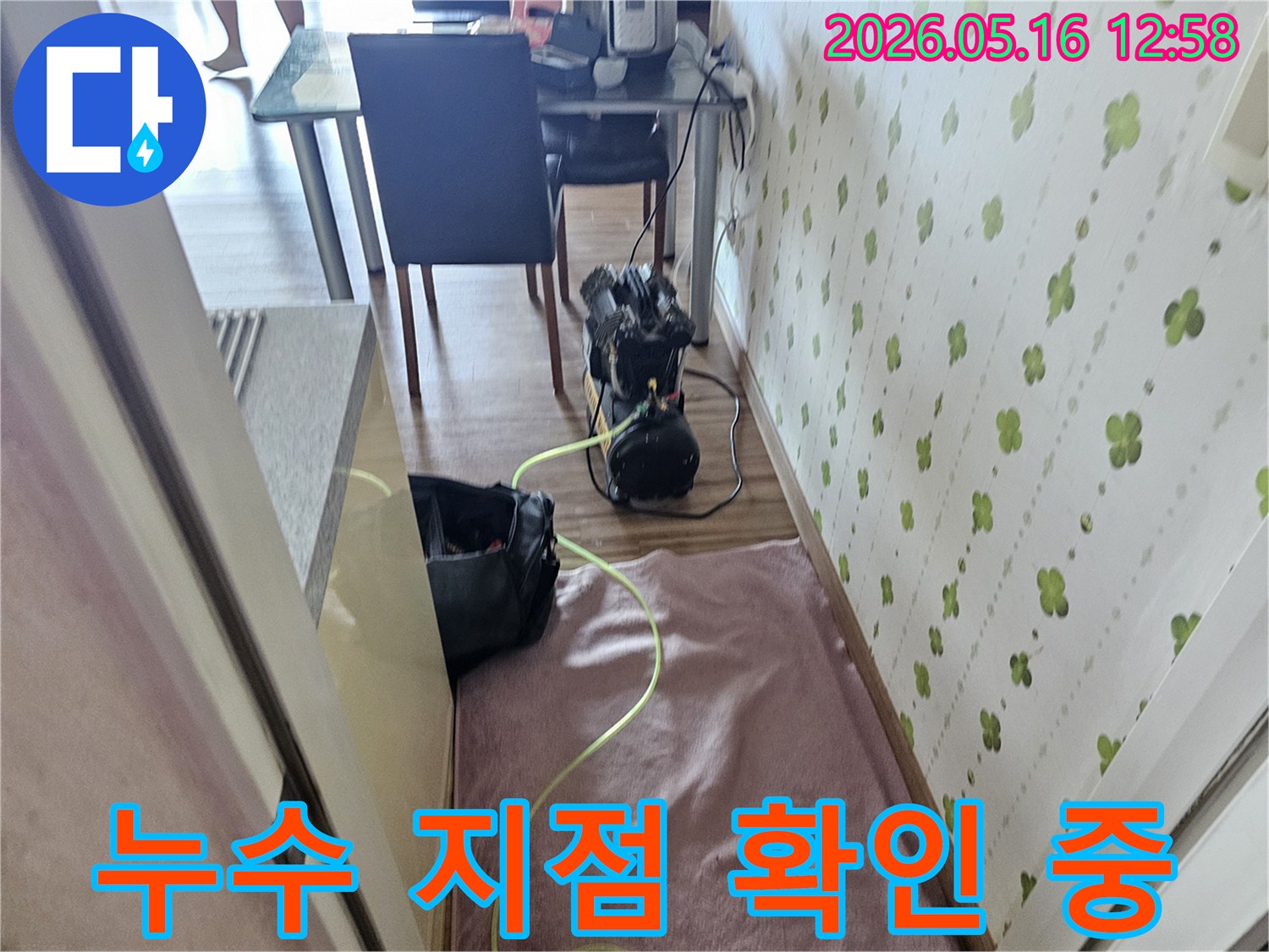 실내 바닥에 놓인 누수 탐지 장비와 연결된 호스가 보입니다-누수 지점을 찾기 위한 필수 과정입니다