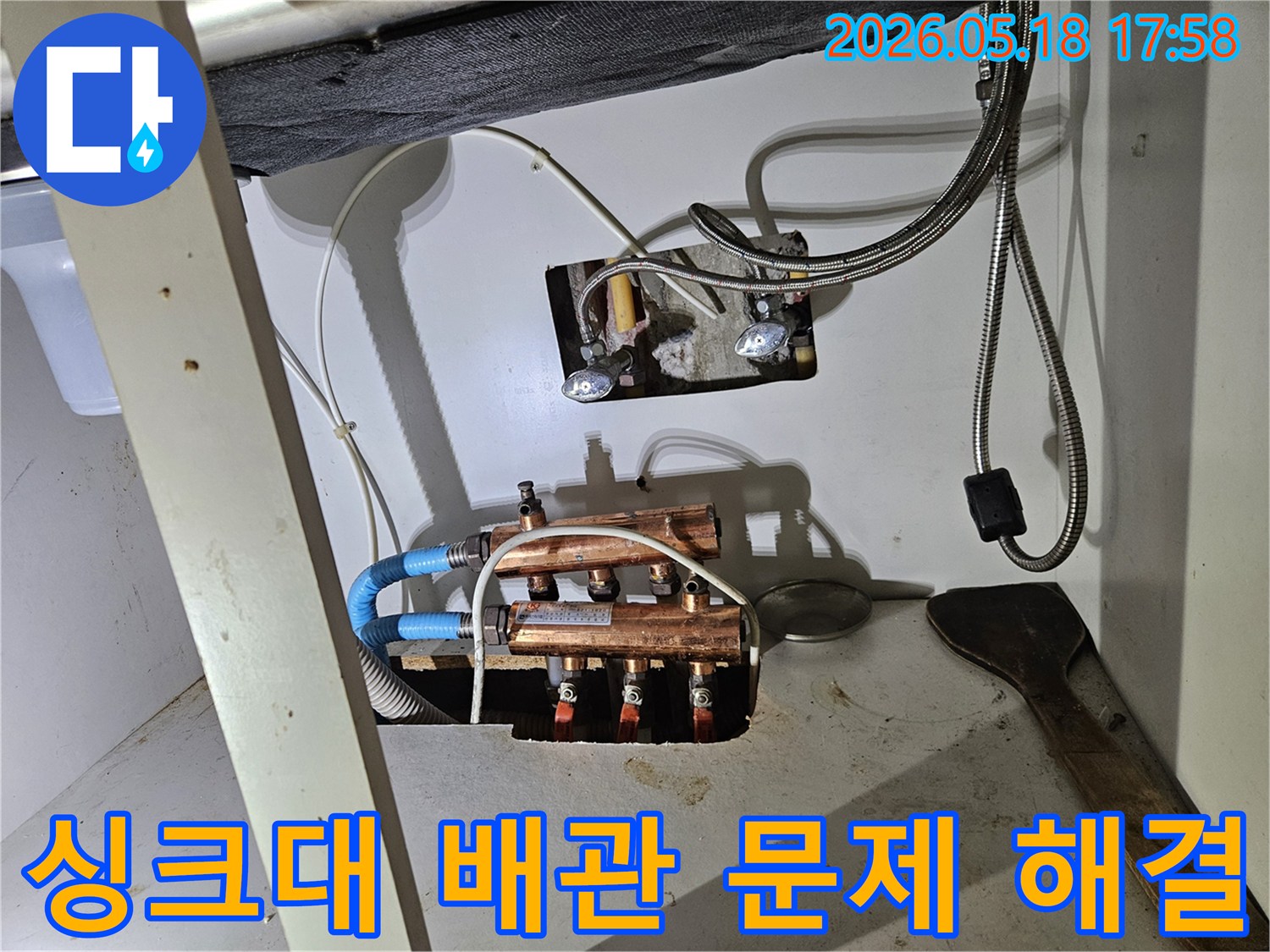 이 이미지는-싱크대 하부에서-발견된 누수 문제를-해결하기 위해-배관을-점검하고-수리하는-과정을 담고 있습니다