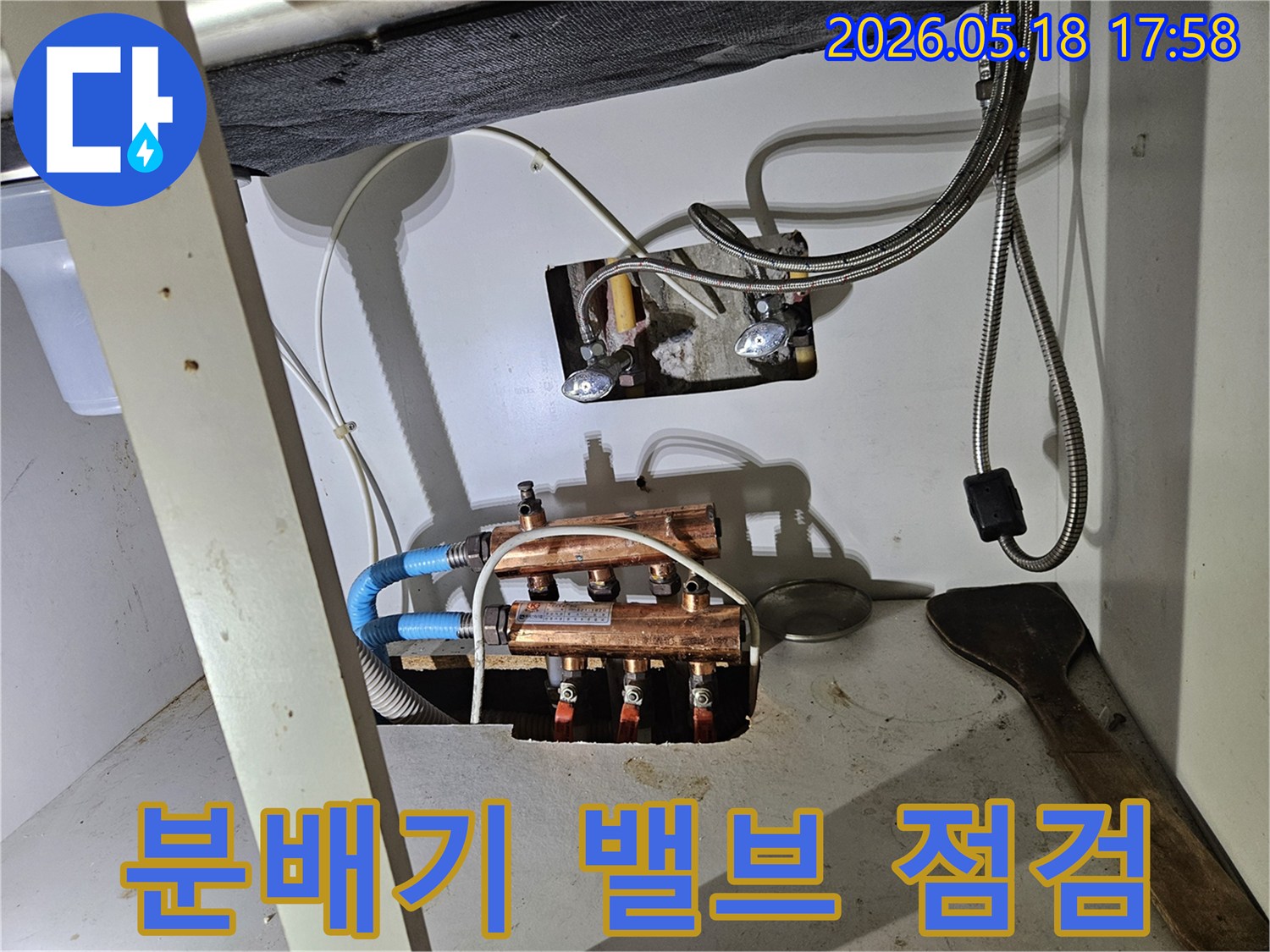 이 이미지는-싱크대 하부의-보일러 분배기에-연결된 밸브들의-상태를-꼼꼼하게-점검하는-모습을 보여줍니다