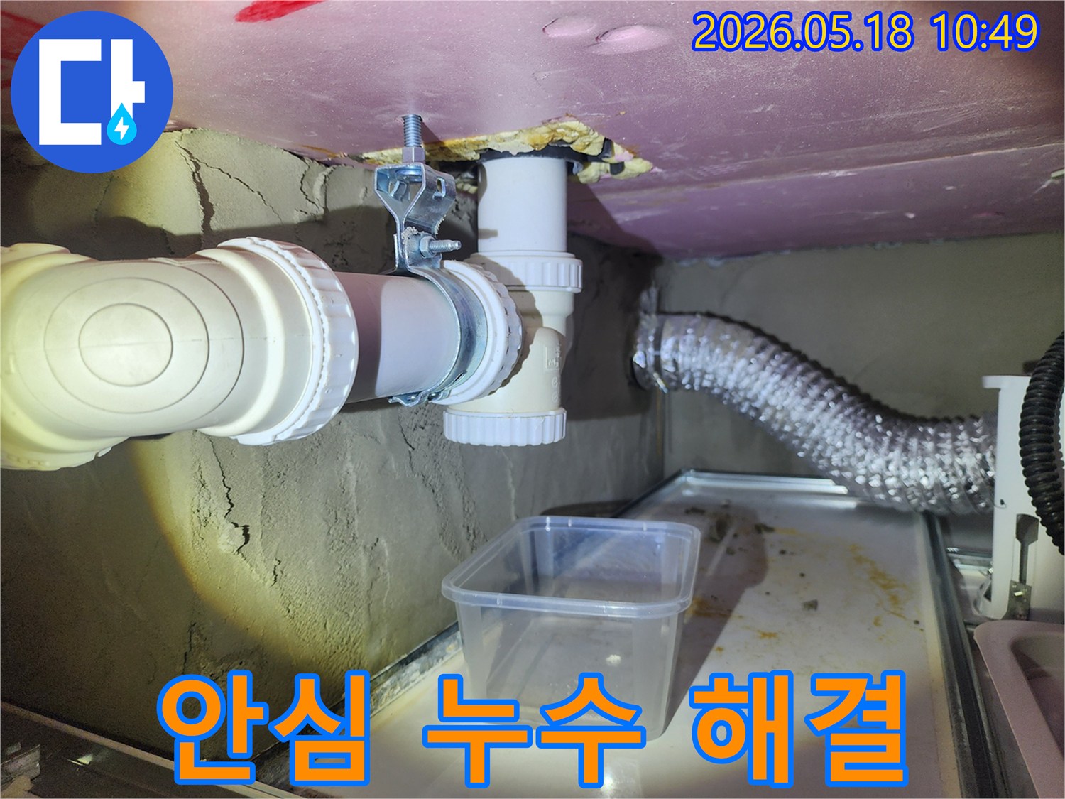 이 사진은 배관 누수 현장에서 물이 떨어지는 것을-임시 용기로 받아내며 안심하고 맡길 수 있는 해결책을 제시하는 모습입니다