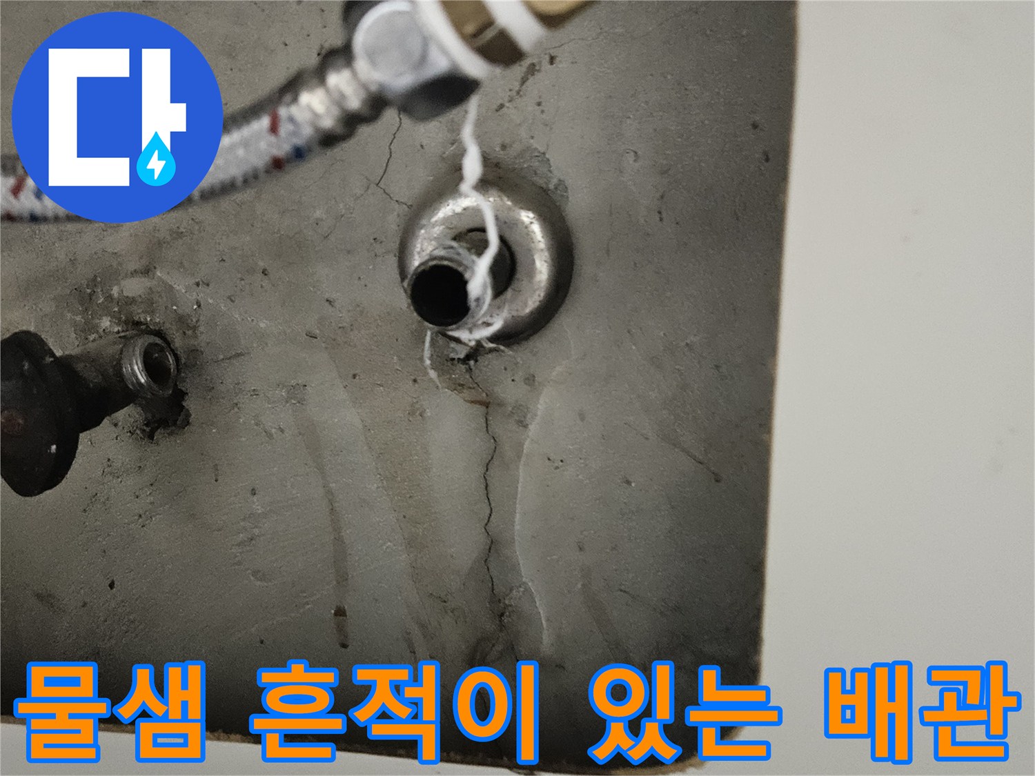 금속 호스와 벽면 배관 사이의 젖은 자국을 상세히 보여주는 사진입니다.