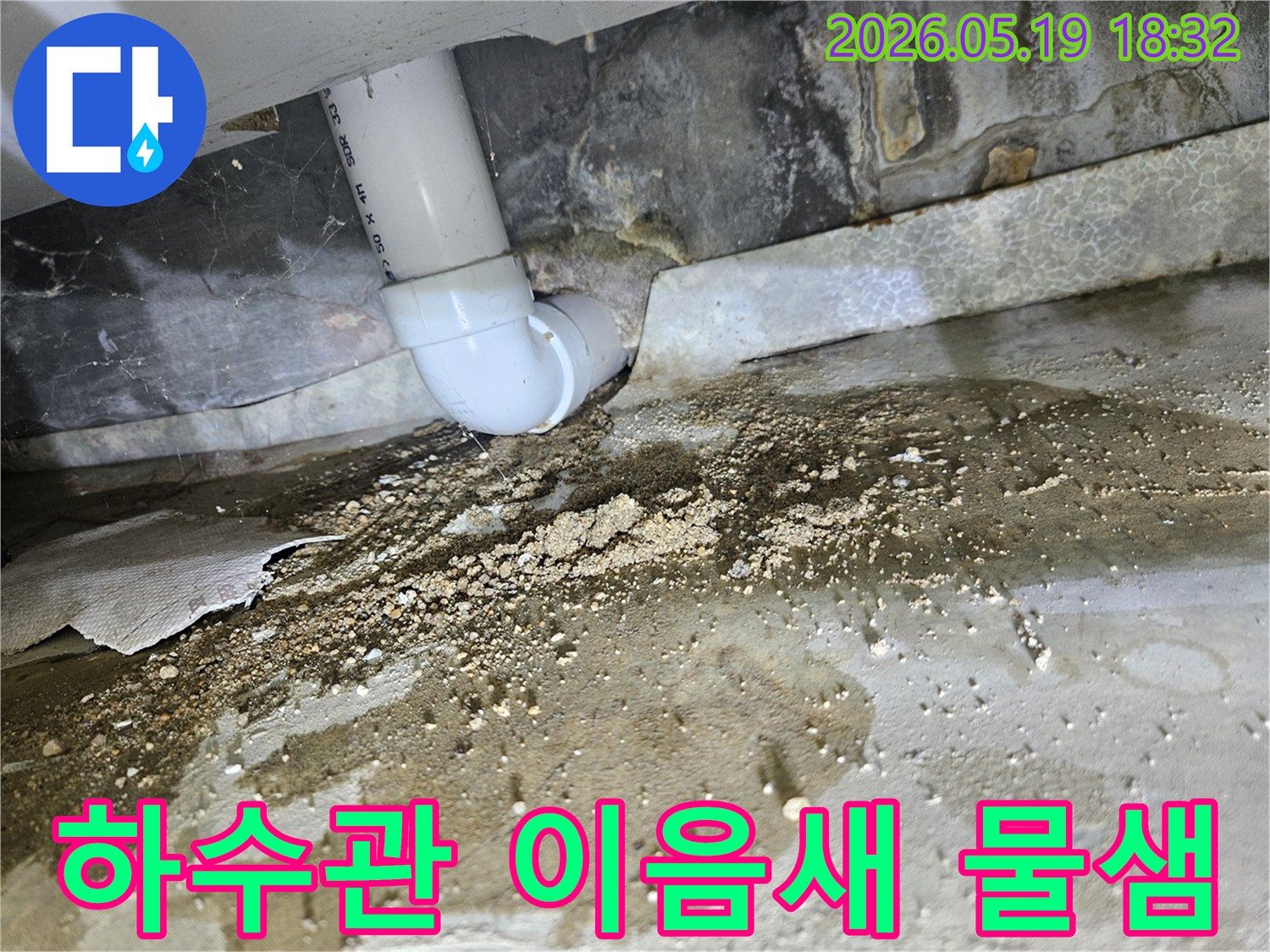서울 노원구의 아파트에서-하수관 연결부의 결함으로 인해-물이 새어 나와-바닥에 습기와 흙먼지가 쌓인-누수 현장입니다.