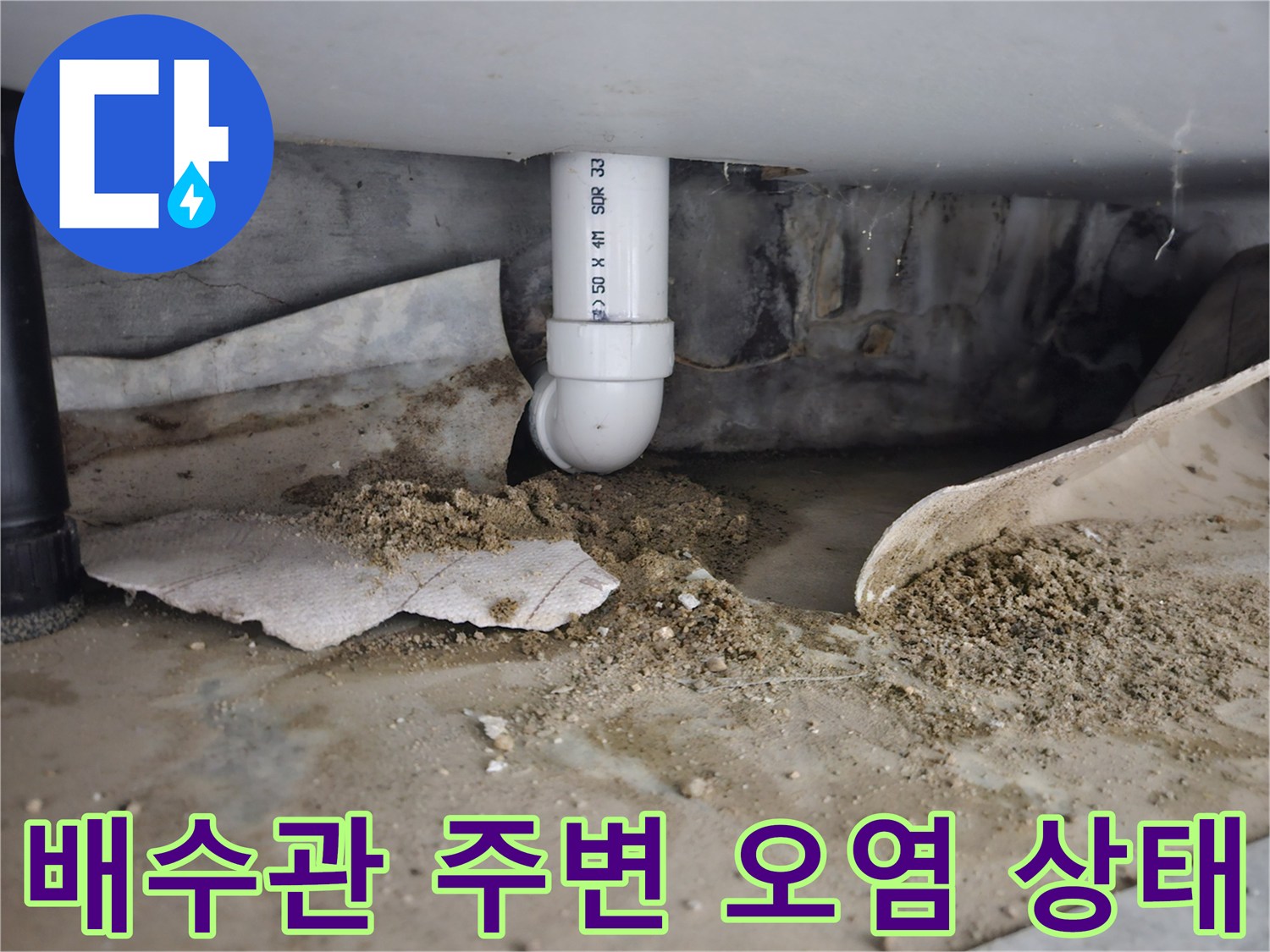 하수 배수관 연결 부위 주변에 젖은 모래와 이물질이 쌓여 있는 모습입니다.