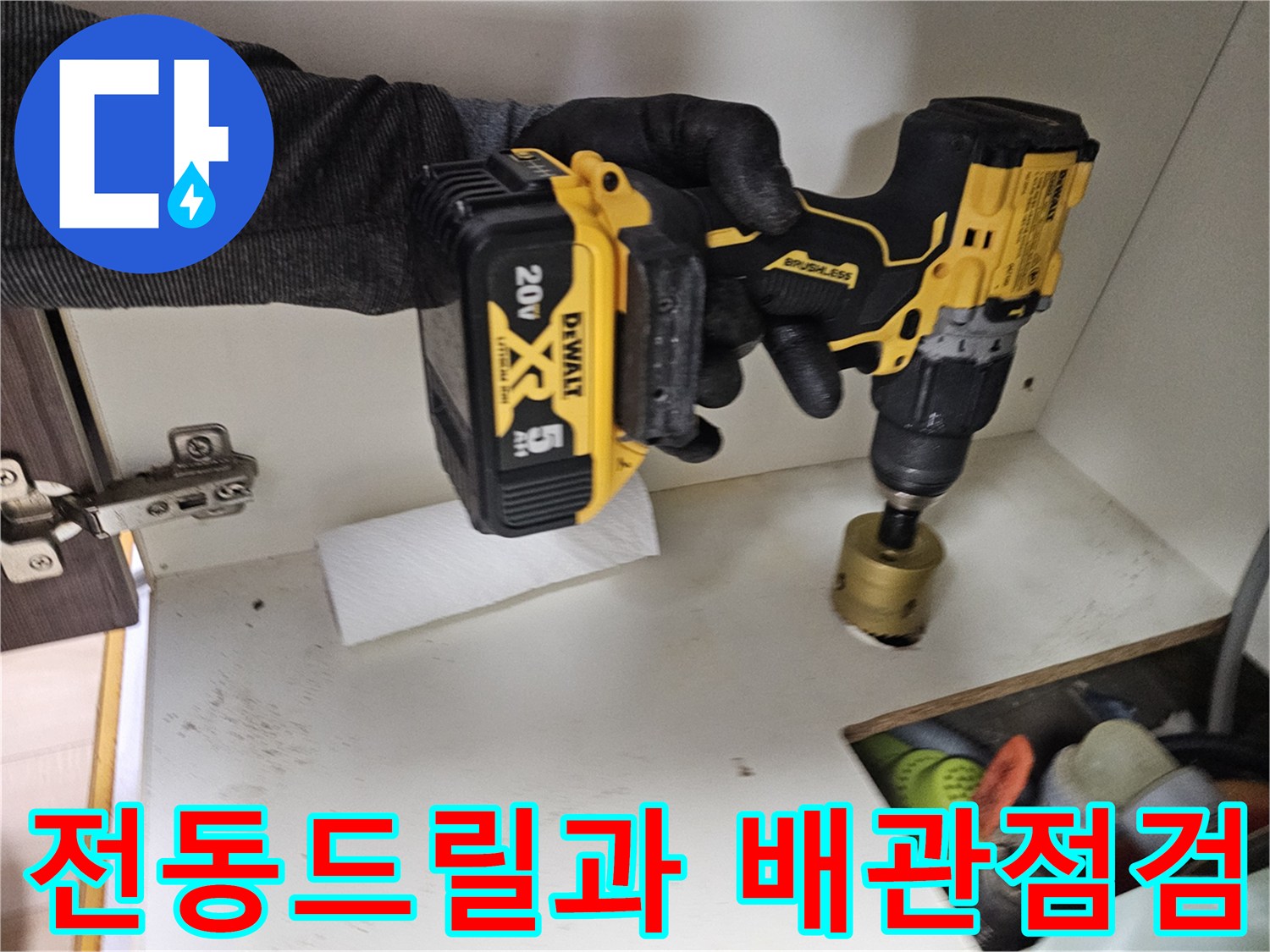 싱크대 하부장 내부에서 전동 드릴을 사용하여 배관 상태를 점검하는 모습