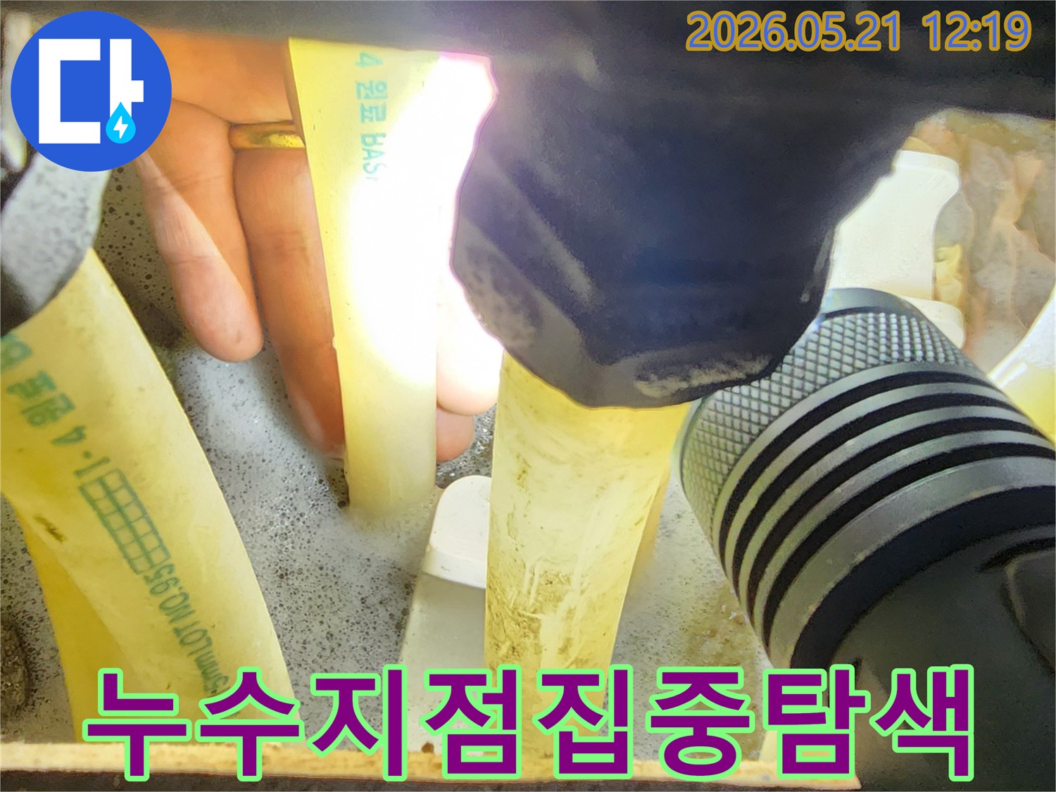 숙련된-누수-엔지니어가-손전등으로-배관-주변의-누수-지점을-집중적으로-탐색하여-원인을-찾는-모습