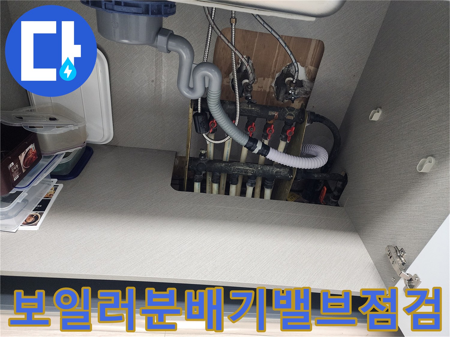 싱크대-하부장-내부의-보일러-분배기와-연결된-흰색-배관들