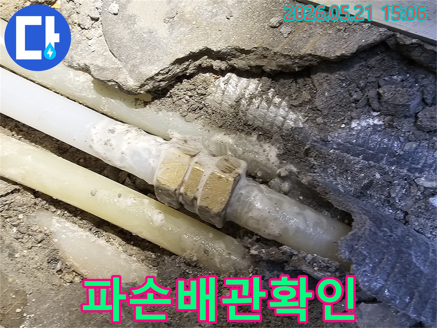 바닥 콘크리트를 깨고 드러난-오래된 수도 배관의-파손된 연결 부위를-자세히 보여주는 사진입니다
