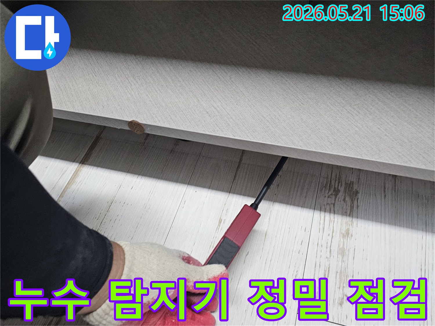 숙련된-엔지니어가-누수-탐지기를-활용하여-가구-틈새의-누수-지점을-정밀하게-조사하는-장면입니다