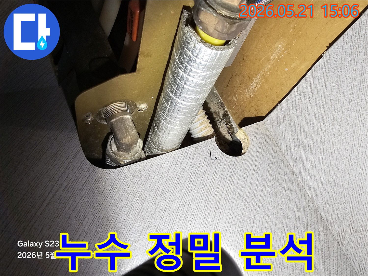 주택 내부의 수도 배관에서 발생한 누수를 진단하기 위해-배관의 상태를 육안으로 확인하고 있는 전문가의 모습입니다