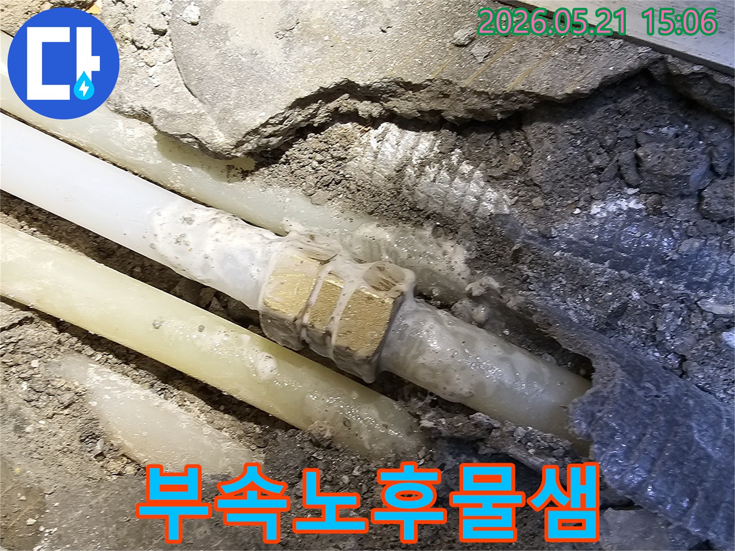 콘크리트 바닥 아래-오래된 수도 배관의-노후된 연결 부속에서-물이 새어 나와-주변을 적시고 있는-누수 현장의 모습입니다
