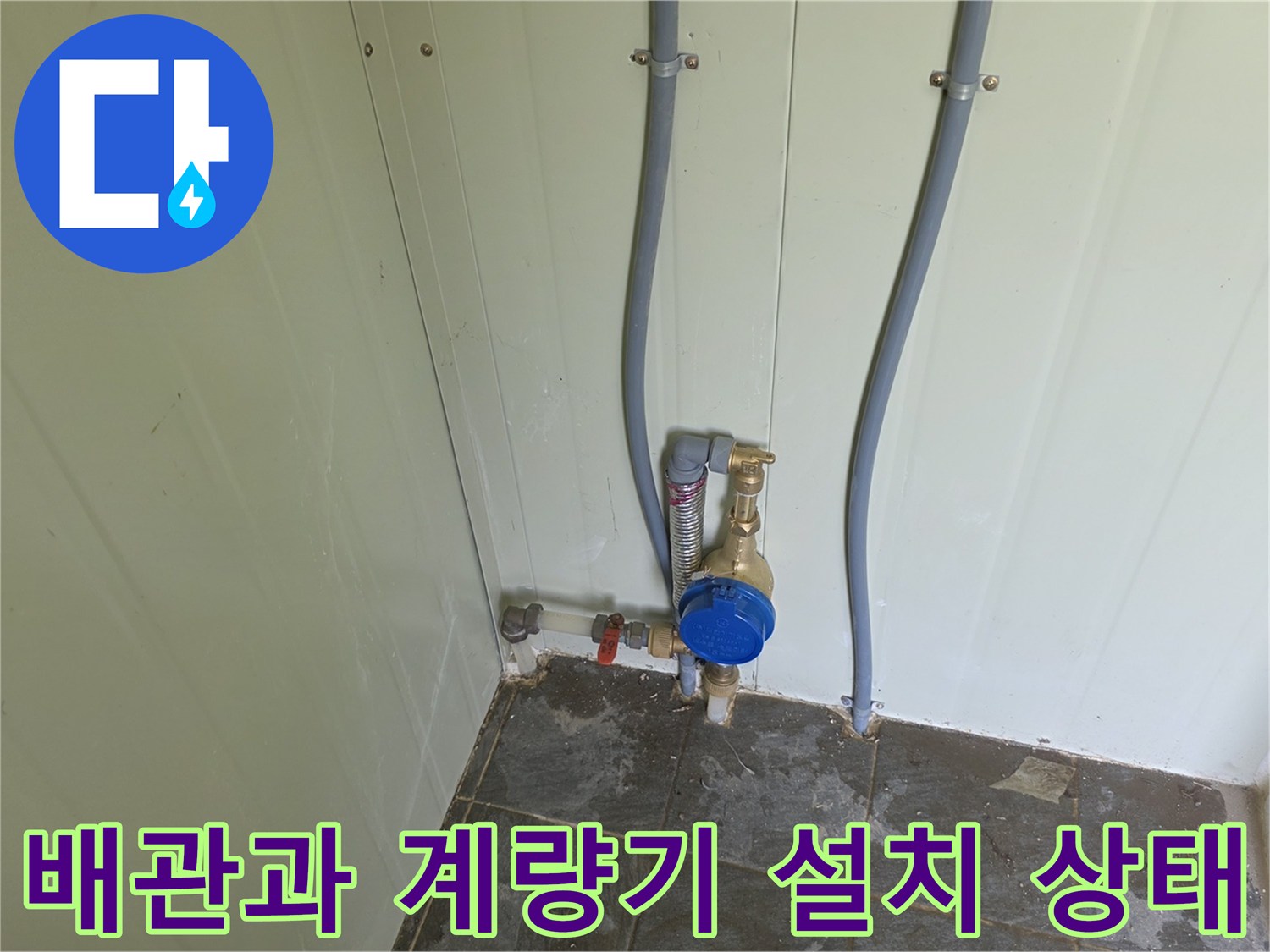 벽면에 고정된 수직 배관과 파란색 수도 계량기 상세 사진