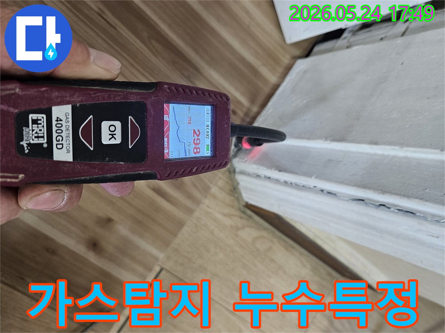 숙련된 누수 엔지니어가 가스 탐지기를 사용하여 벽면 하단에서 누수 반응을 면밀히 확인하고 있습니다.