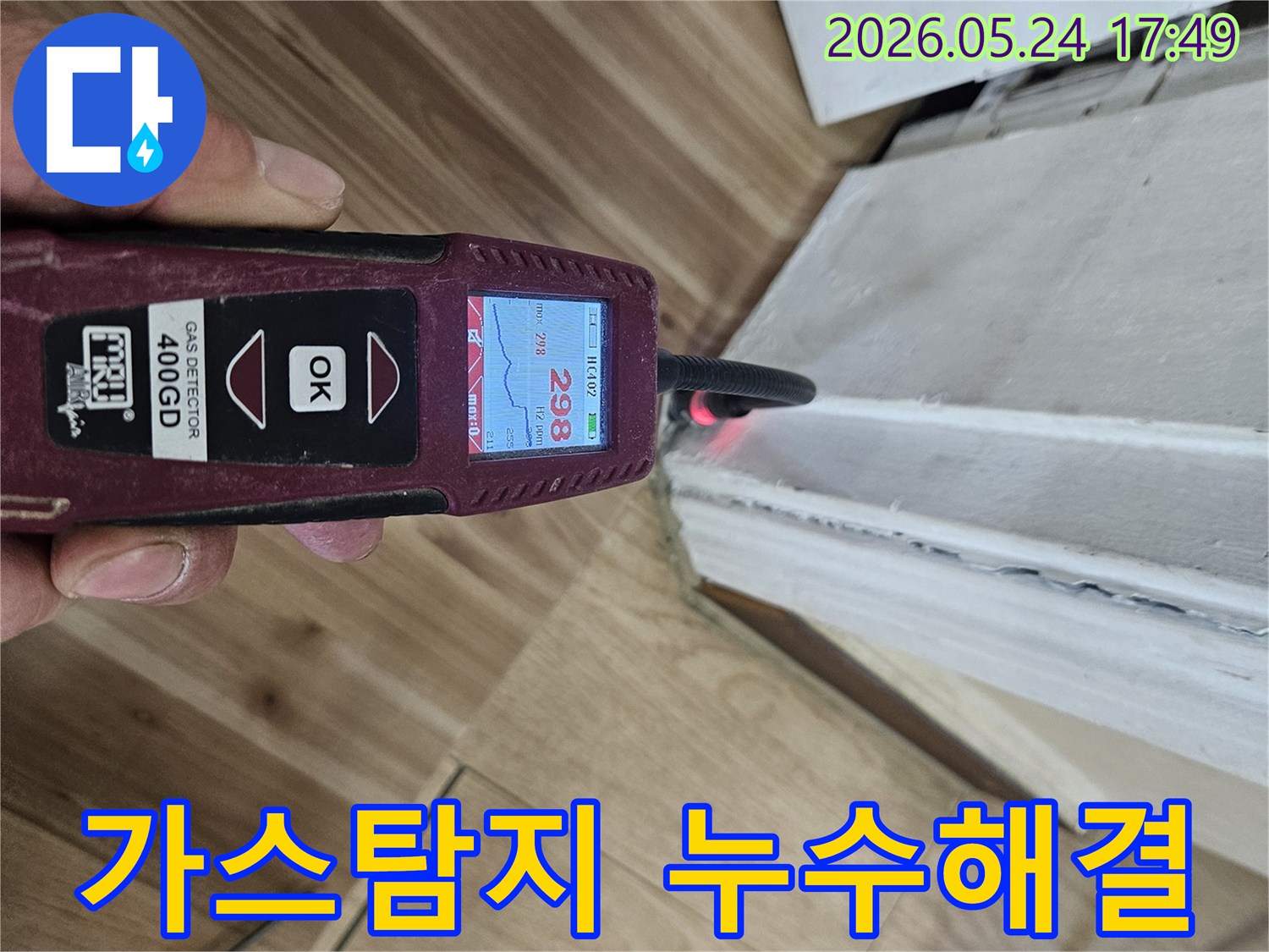 숙련된 누수 엔지니어가 가스 탐지기를 사용하여 벽면 하단에서 누수 반응을 면밀히 확인하고 있습니다.