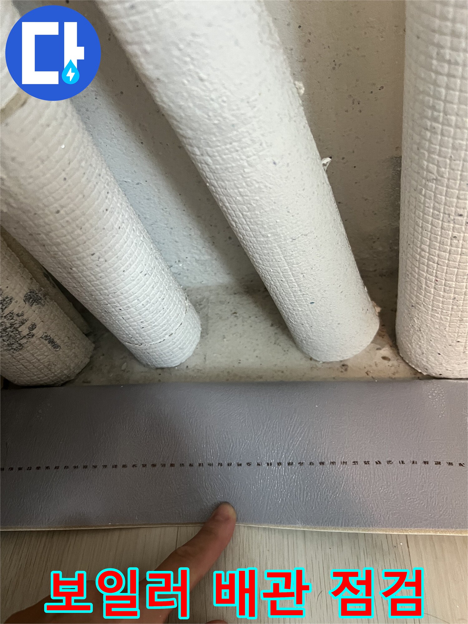 하얀색 보온재로 덮인 배관과 아래쪽 마감재의 모습