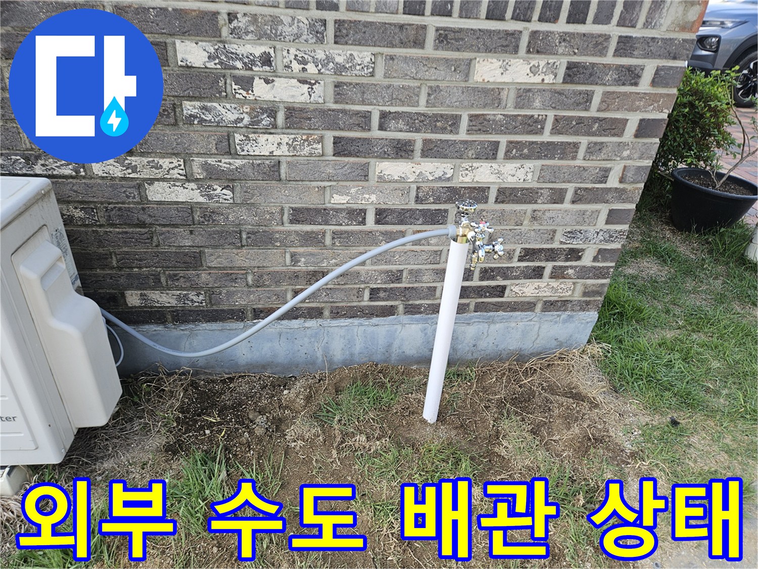 벽돌 외벽에 설치된 외부 수도꼭지와 연결 배관 모습입니다.
