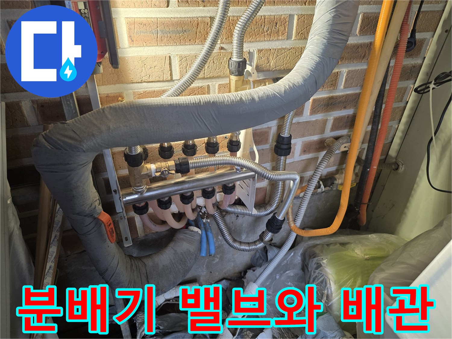 벽돌 벽면에 설치된 금속제 분배기와 유연한 호스들