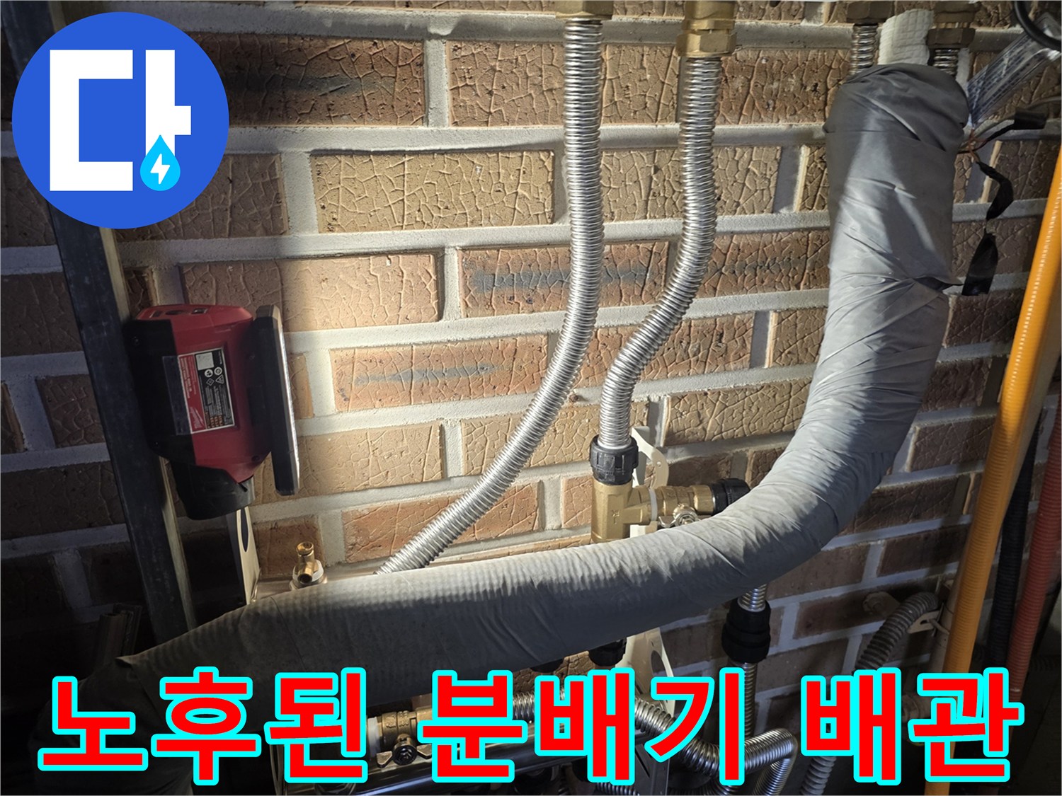 벽돌 벽면의 은색 배관들과 보온재로 감싸진 수도 연결 부위