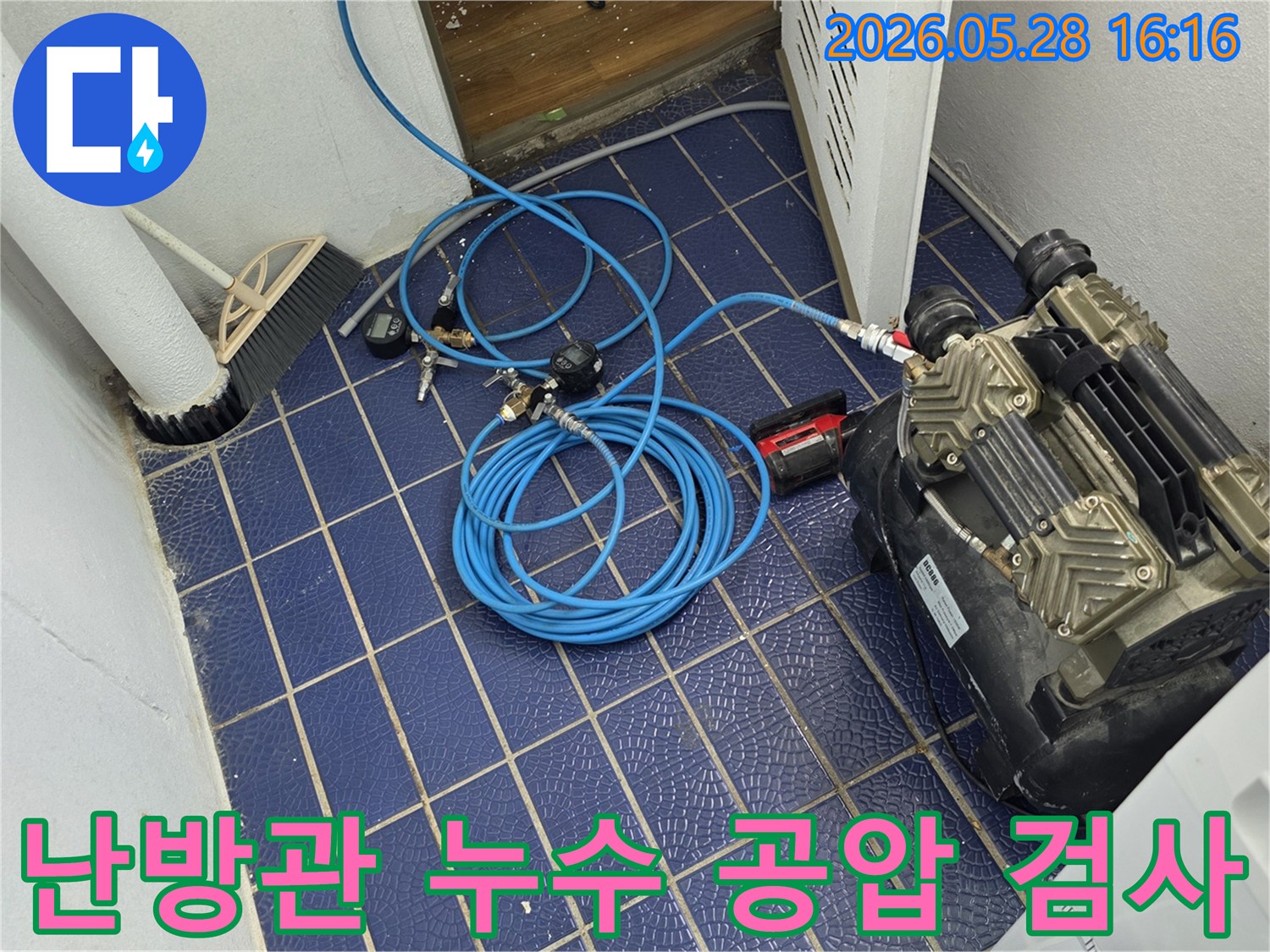 난방관-누수-원인을-찾기-위해-배관에-연결된-공압-장비와-압력-게이지-그리고-파란색-호스가-보이는-작업-현장
