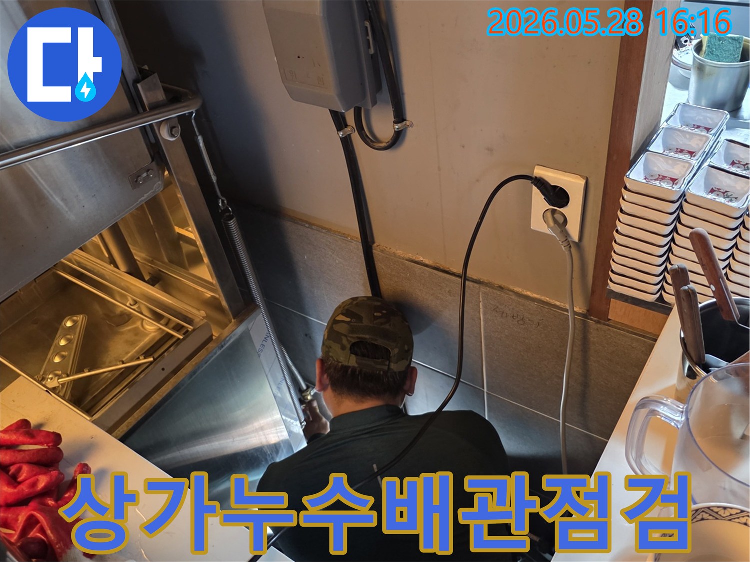 누수 전문가가-상가 주방 후드 아래-복잡한 배관 구조를-세밀하게 점검하는 모습