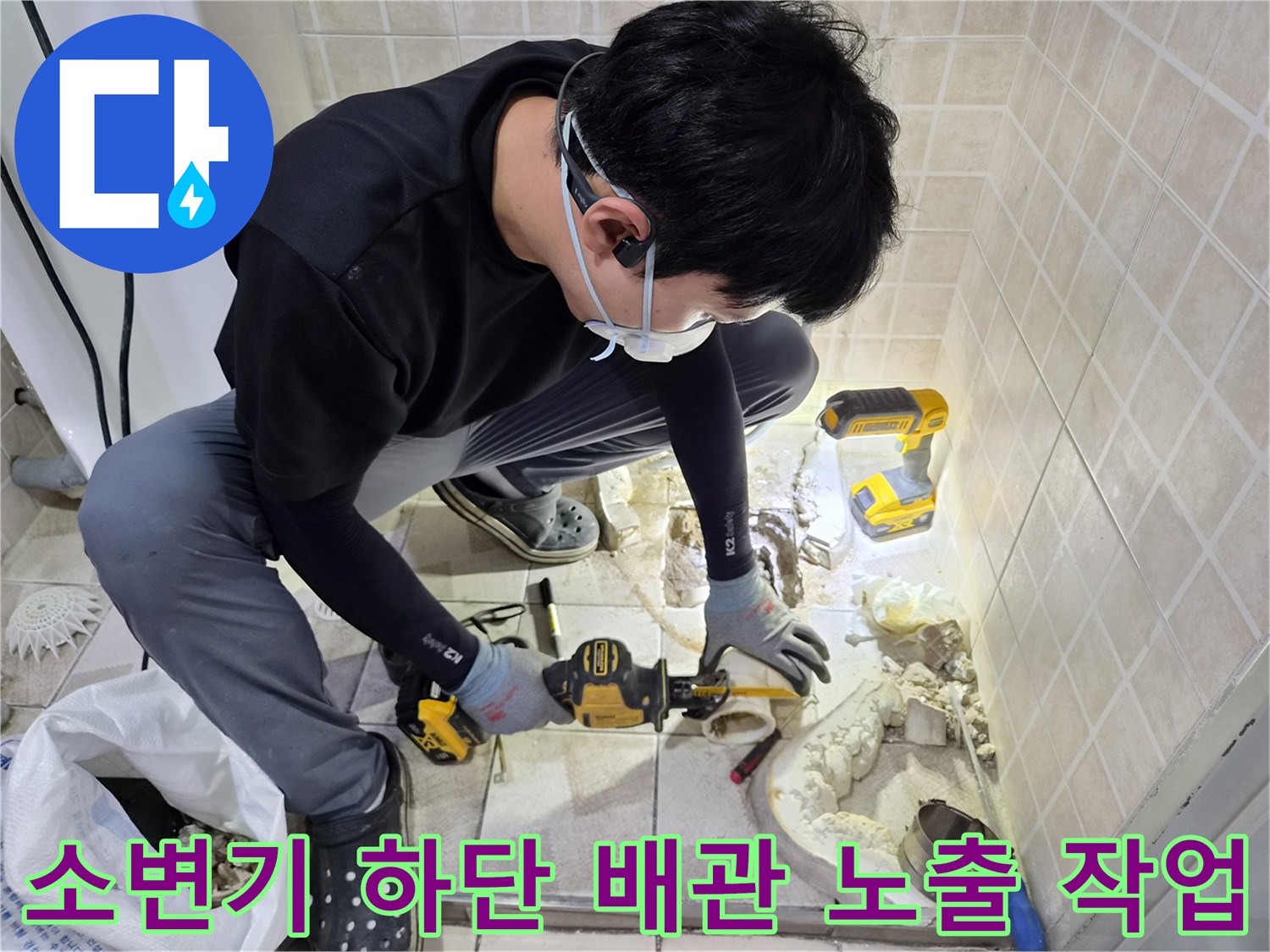 굴착된 바닥 사이로 드러난 소변기 연결 배관과 점검 중인 작업자