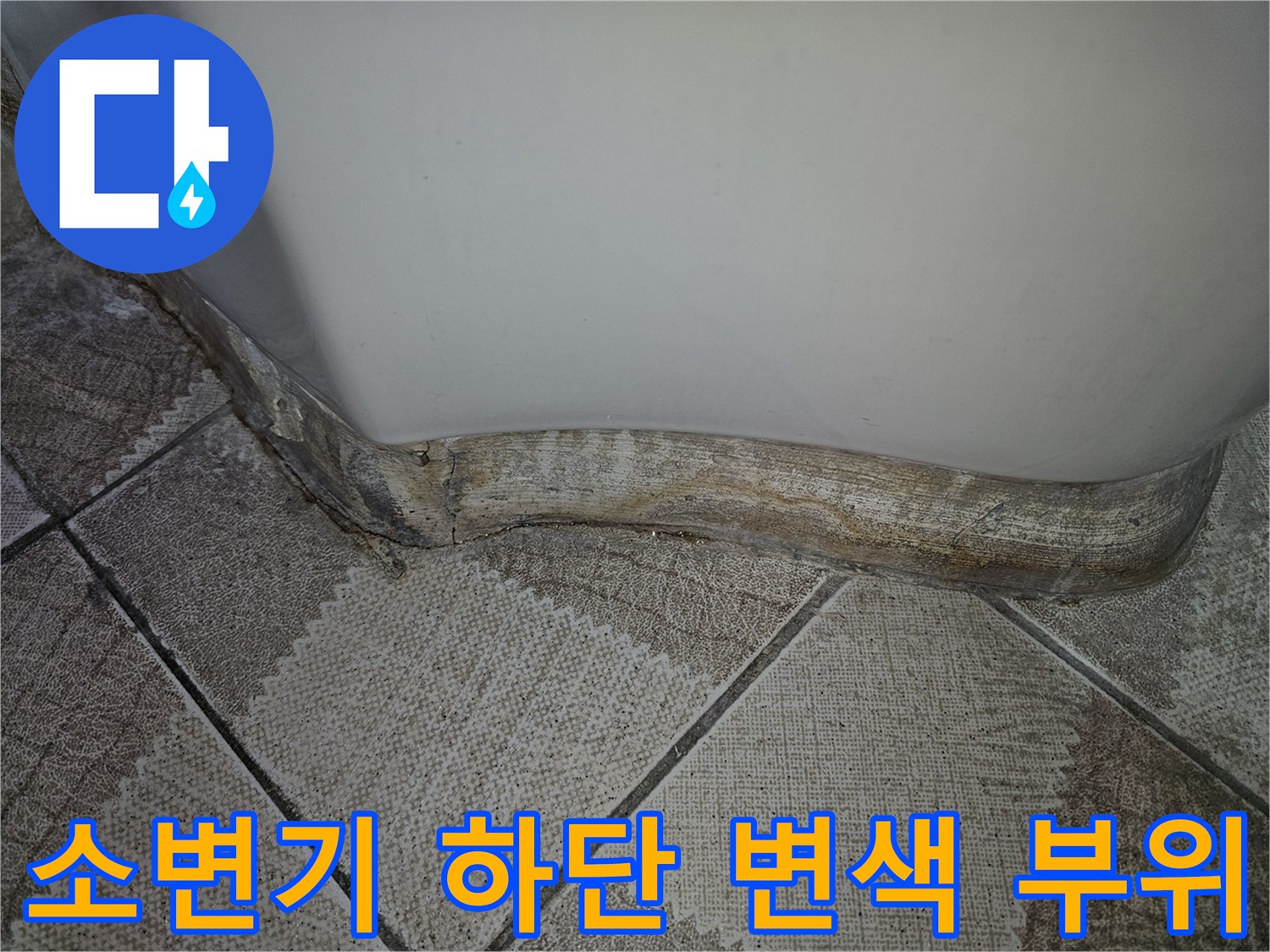소변기 밑부분-누수로 인해 젖고 변색된 타일 경계