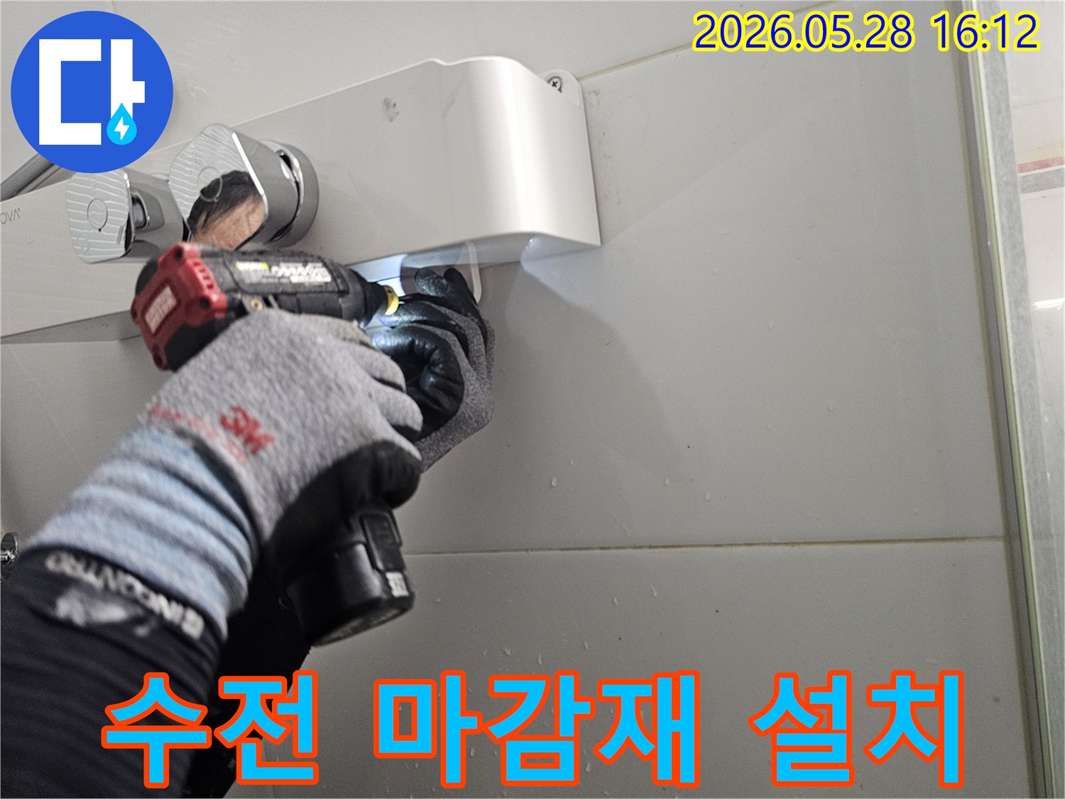 전문 기술자가-보호 장갑을 착용하고-전동 공구로-샤워기 수전의-마감재를-깔끔하게-설치하는-모습입니다