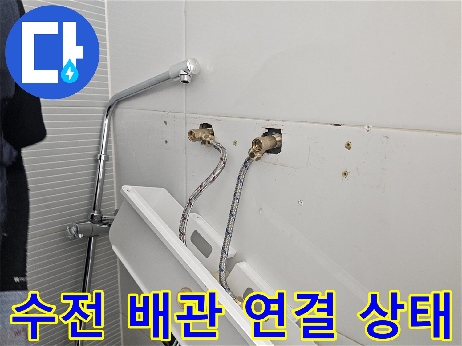 화이트 타일 벽면에 노출된 냉온수 배관과 고압 호스 연결 모습