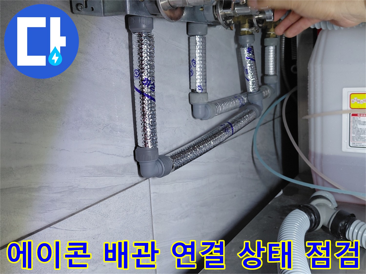 손으로 에이콘 배관의 금속 부속 연결 부분을 짚으며 확인하는 작업 장면