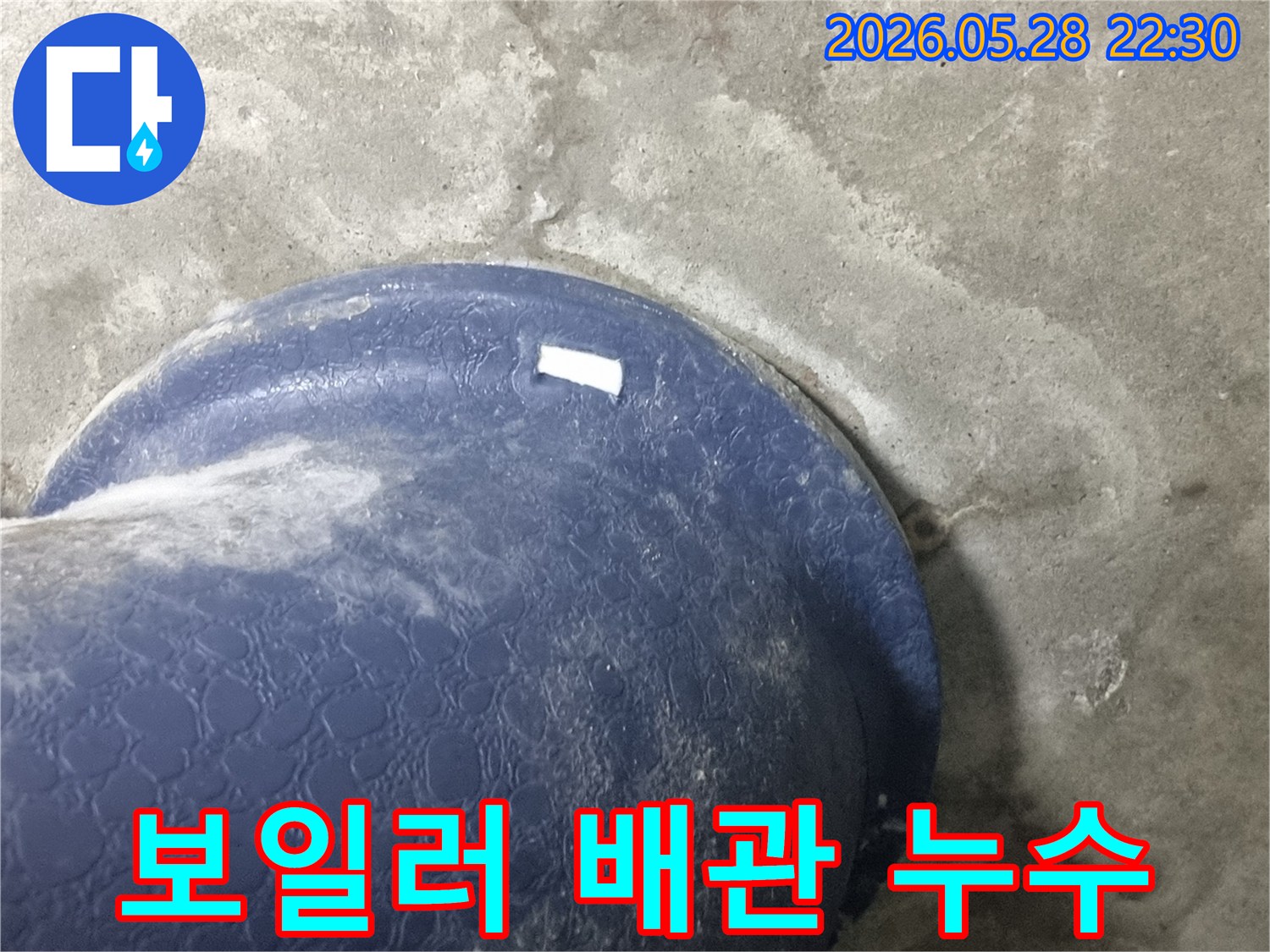 콘크리트 바닥의-파란색 보일러-배관-주변으로-물이-새어-나와-젖은-모습을-보여주는-현장-사진