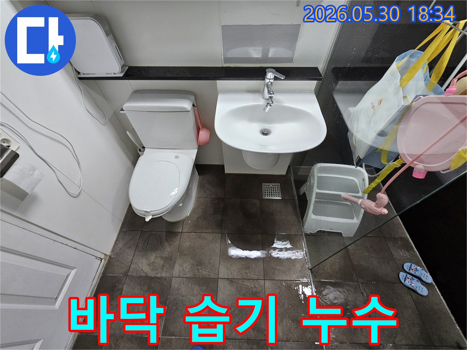 타일-바닥에-고인-물과-젖은-표면은-화장실-내부에서-발생한-누수-문제를-시각적으로-증명합니다