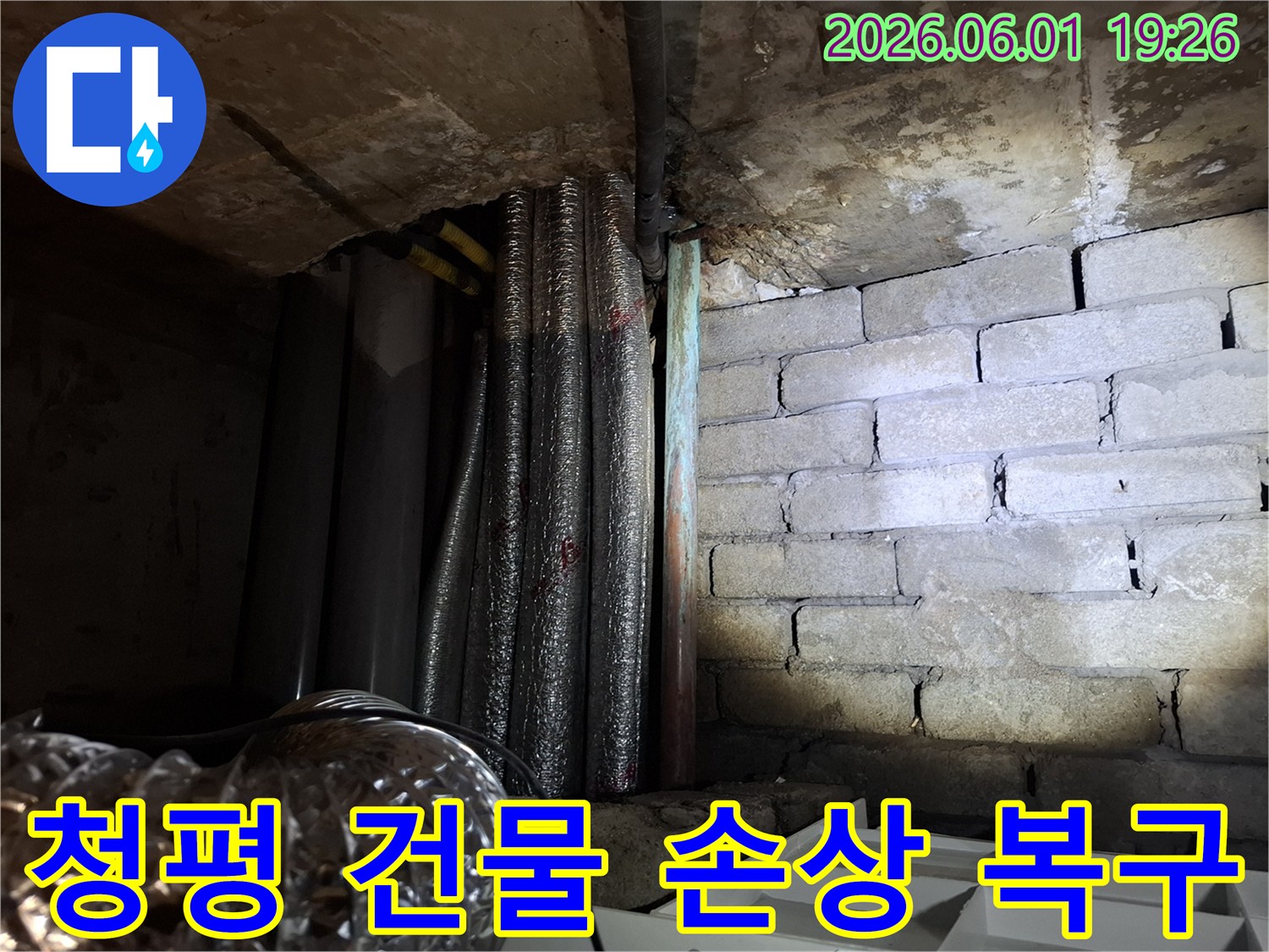 어두운 지하 공간에서-손상된 배관과-물에 젖은 벽돌 벽면이-보이는 누수 현장입니다